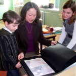 Kotryna Karyznaitė su savo mama ir broliuku varto rankų darbo knygą